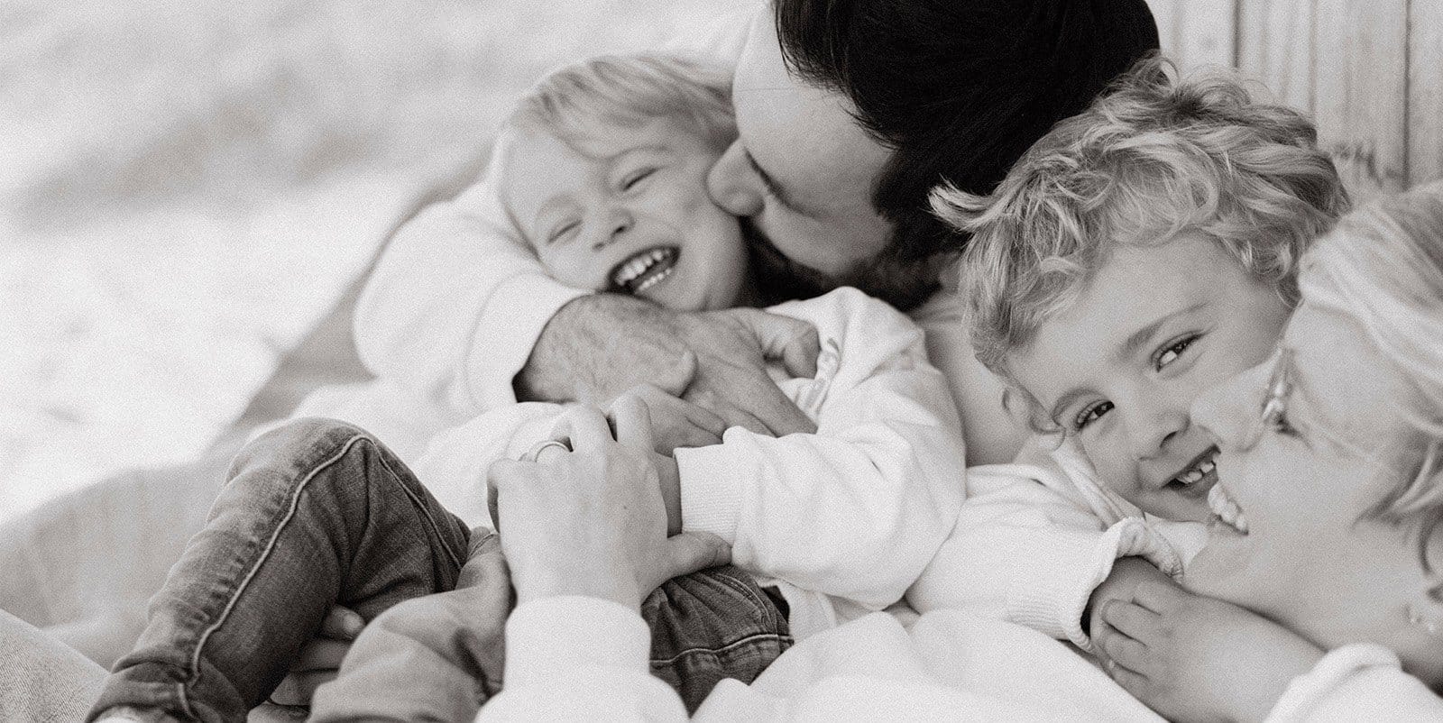 Parents et trois enfants qui rient, séance famille en noir et blanc