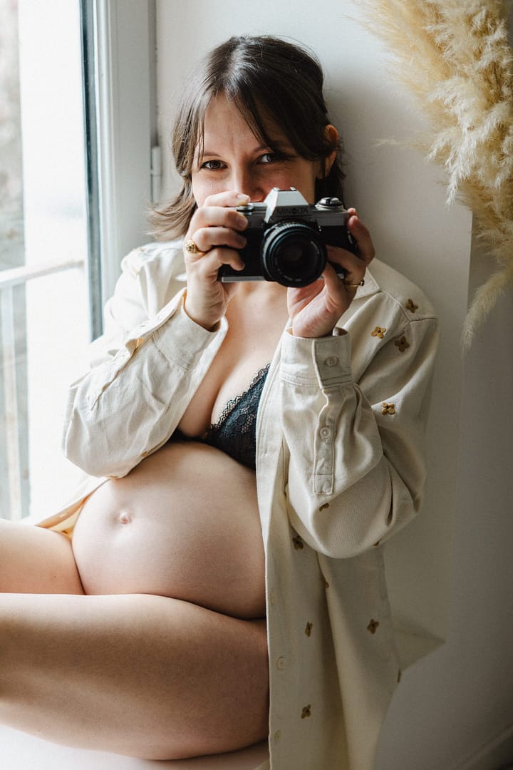 Future maman avec un appareil photo, séance en intérieur
