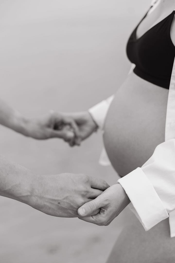 Mains sur le ventre en noir et blanc, séance grossesse
