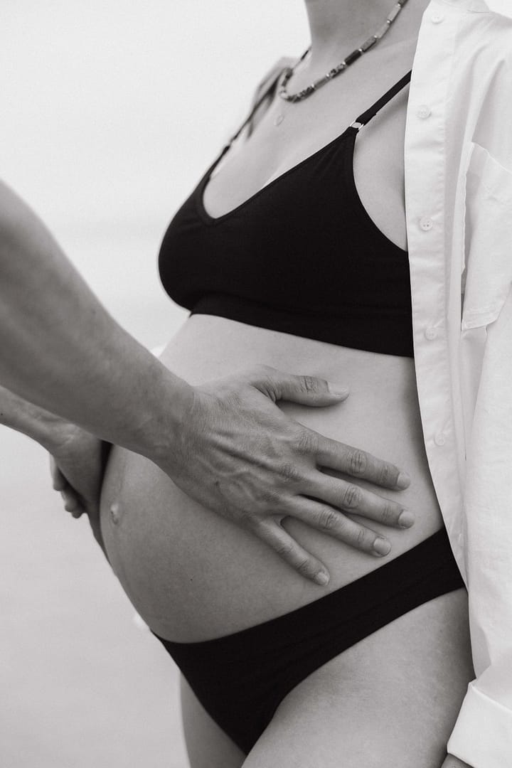 Ventre de future maman en noir et blanc, fond sombre
