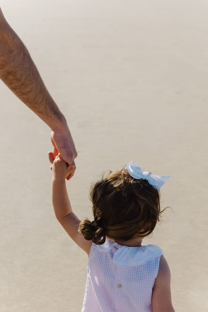 Main d'un adulte et d'un enfant sur la plage